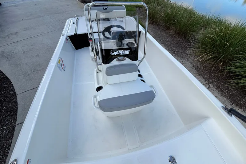 Slide: The Image of 2026 Mako Pro Skiff 17 CC boat with center console, docked near lush greenery. - 10