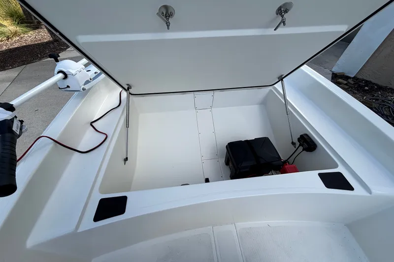 Slide: The Image of 2026 Mako Pro Skiff 17 CC boat storage compartment with open lid and visible battery. - 8