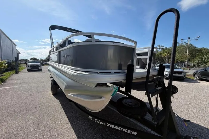 Slide: The Image of 2026 Sun Tracker Bass Buggy 18 DLX pontoon boat on trailer in parking lot. - 4