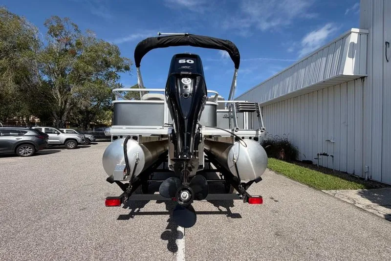 Slide: The Image of 2026 Sun Tracker Bass Buggy 18 DLX pontoon boat with outboard motor in parking lot. - 6