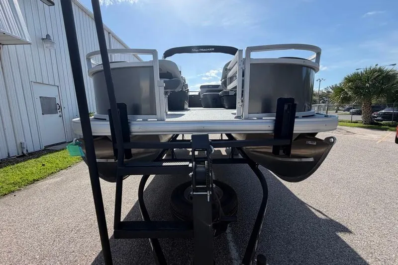 Slide: The Image of 2026 Sun Tracker Bass Buggy 18 DLX pontoon boat on trailer, parked outdoors. - 3