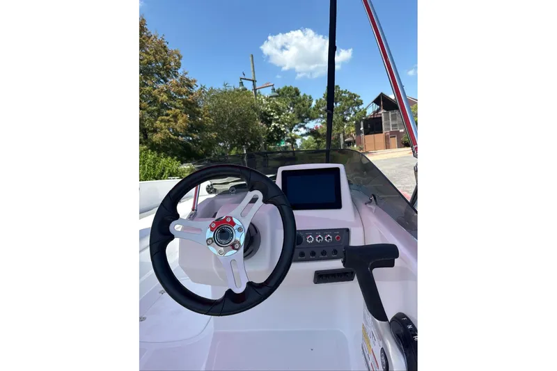 Slide: The Image of 2026 Tahoe T18 boat dashboard with steering wheel and control panel under clear blue sky. - 6