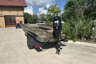 Slide: The Image of 2026 Tracker Grizzly 1756 T Marsh boat on trailer, parked outdoors near greenery. - 2