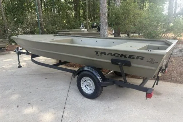 The Image of 2026 Tracker Grizzly 1754 Utility boat on trailer in wooded area. - 0
