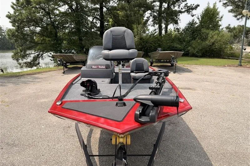Slide: The Image of 2026 Tracker Bass Tracker Classic XL boat with red trim, parked near a lake. - 2