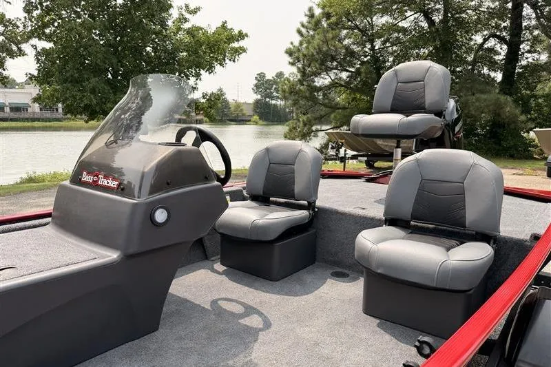 Slide: The Image of 2026 Tracker Bass Tracker Classic XL boat interior with three gray seats by a lake. - 8