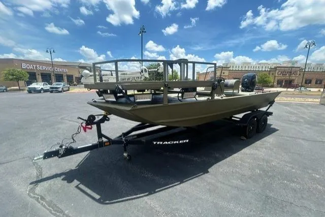 Slide: The Image of 2026 Tracker Grizzly 2072 CC Sportsman boat on trailer, parked outdoors under blue sky. - 2