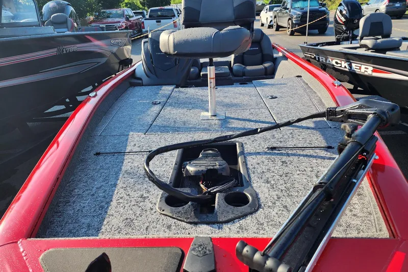 Slide: The Image of 2026 Tracker Pro Team 190 boat with red exterior and fishing deck, parked outdoors. - 3