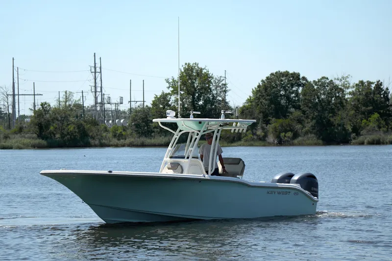 Slide: The Image of 2021 Key West 244 Center Console boat cruising on a calm river with trees in the background. - 2