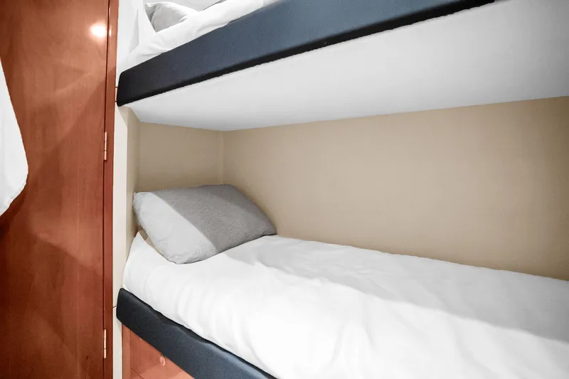 Slide: The Image of Bunk beds in 2008 Hatteras 77 Convertible yacht cabin, featuring wooden paneling and cozy bedding. - 102