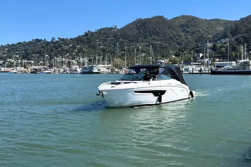 Slide: The Image of 2023 Cruisers Yachts 34 GLS I/O navigating a scenic marina with hills in the background. - 1