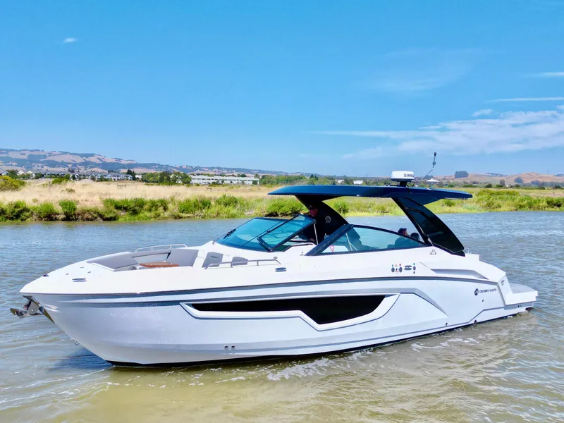 Slide: The Image of 2023 Cruisers Yachts 34 GLS I/O on a sunny day, cruising on a calm river. - 2