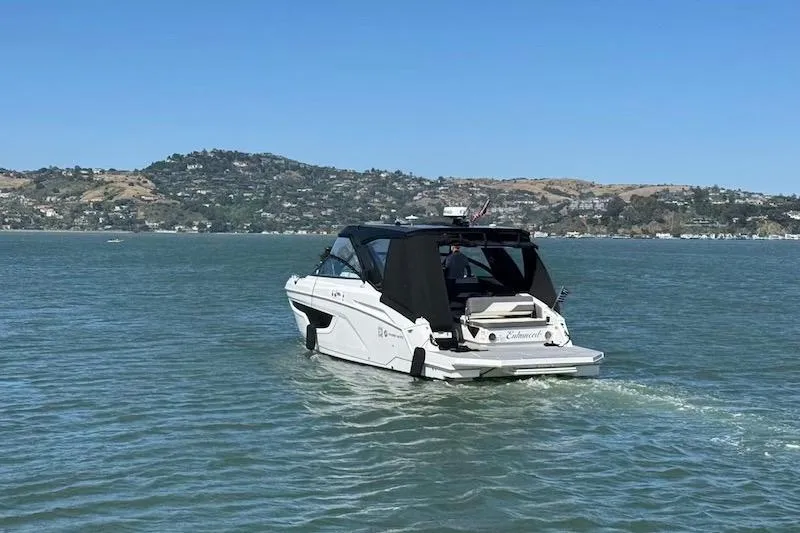 Slide: The Image of 2023 Cruisers Yachts 34 GLS I/O navigating scenic waters with hills in the background. - 76