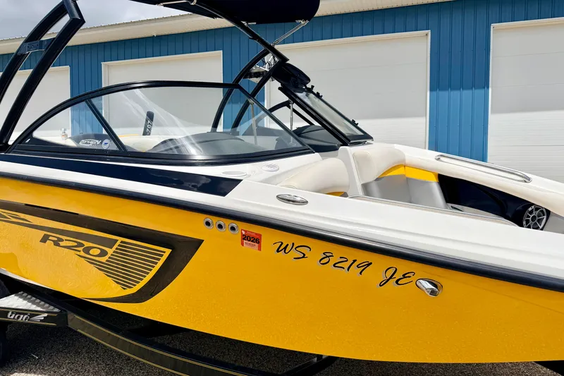 Slide: The Image of 2014 Tigé R20 boat with yellow and black design, parked near a blue building. - 10
