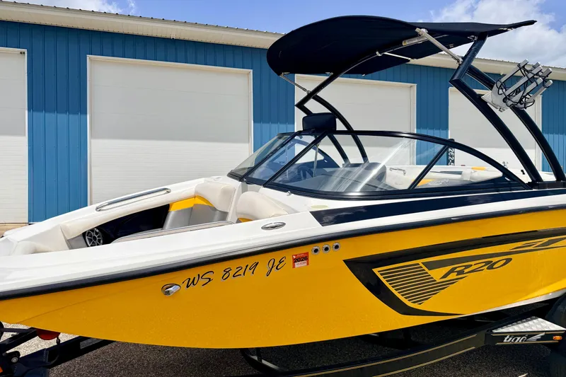 Slide: The Image of 2014 Tigé R20 boat with yellow hull, parked near blue building. - 12