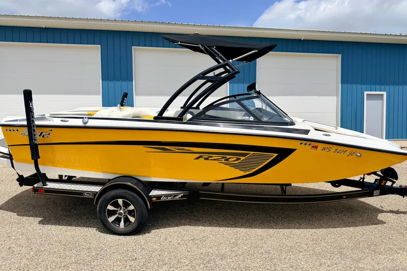 Slide: The Image of 2014 Tigé R20 boat in vibrant yellow, parked on a trailer near a blue building. - 7