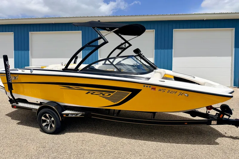 Slide: The Image of 2014 Tigé R20 boat in vibrant yellow, parked on a trailer near blue garage doors. - 3