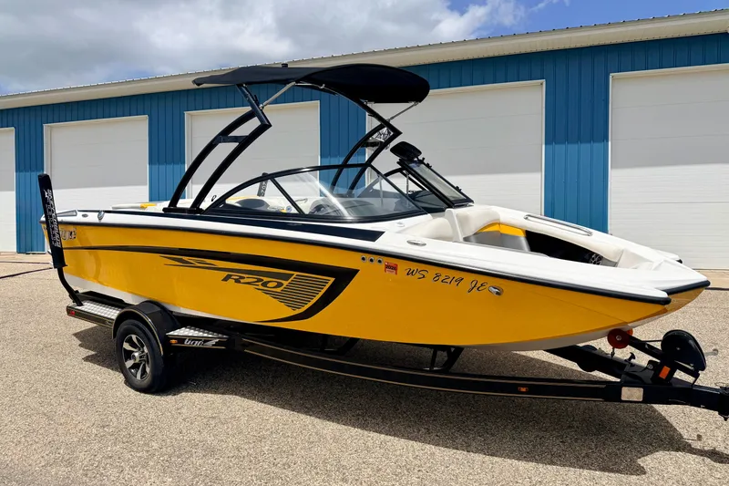 Slide: The Image of 2014 Tigé R20 yellow boat on trailer, parked outside blue building. - 5