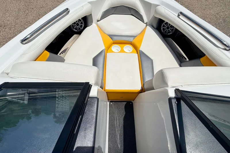 Slide: The Image of 2014 Tigé R20 boat interior with white and yellow seating, cup holders, and speakers. - 55