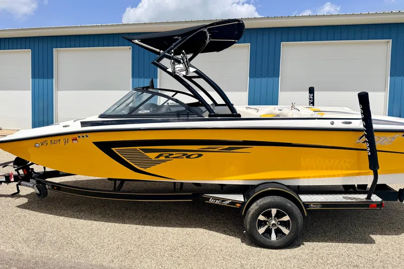 Slide: The Image of 2014 Tigé R20 boat in vibrant yellow, parked on a trailer near blue garage doors. - 8
