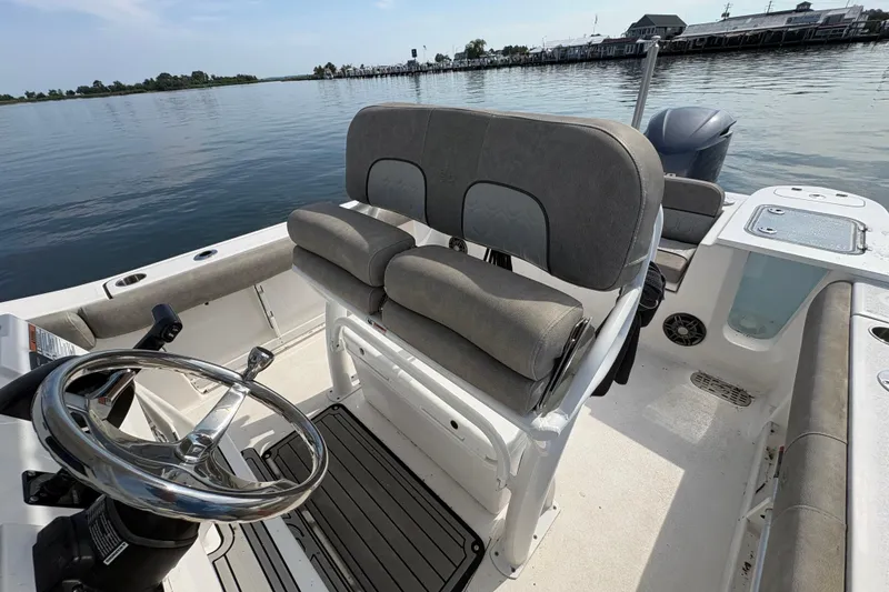 Slide: The Image of 2022 Sea Fox 248 Commander boat interior with steering wheel and seating, docked on calm water. - 3