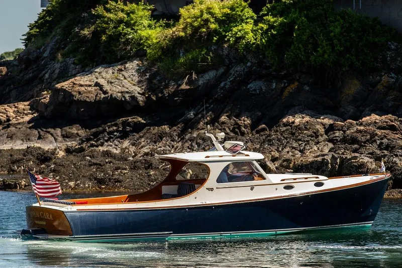 The Image of Hinckley Picnic Boat 36 Classic, 2000 model, cruising near rocky shoreline with American flag. - 0