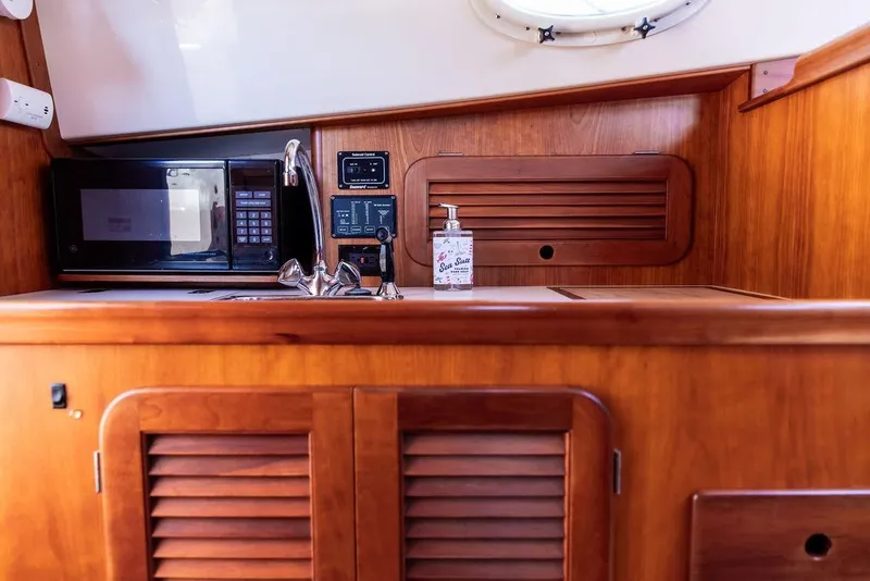 Slide: The Image of Hinckley Picnic Boat 36 Classic 2000 interior with wooden cabinetry, microwave, and sink. - 13