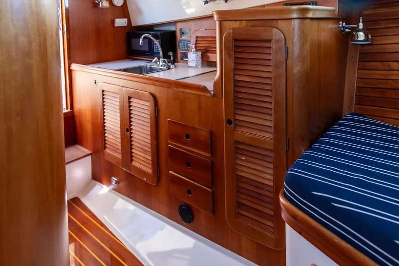 Slide: The Image of Interior of 2000 Hinckley Picnic Boat 36 Classic with wooden cabinetry and striped seating. - 14