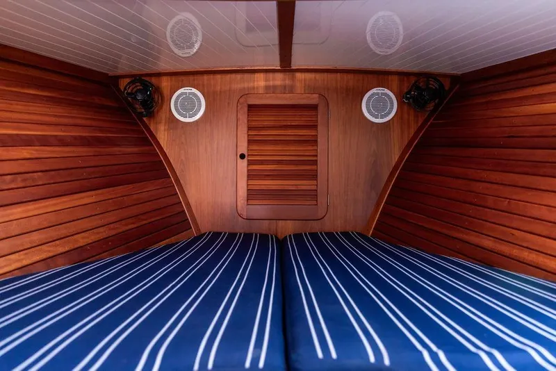 Slide: The Image of Interior cabin of 2000 Hinckley Picnic Boat 36 Classic with striped bedding and wooden paneling. - 16