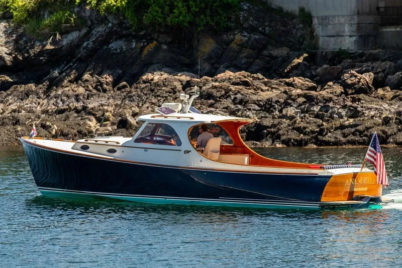 Slide: The Image of Hinckley Picnic Boat 36 Classic, 2000 model, cruising near rocky shoreline. - 23