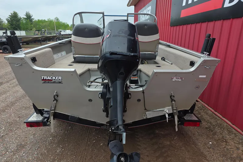 Slide: The Image of 2005 Tracker Pro Guide V-16 WT boat with outboard motor, parked near a red building. - 5