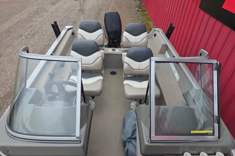 Slide: The Image of 2005 Tracker Pro Guide V-16 WT boat interior with seating and windshield, parked near a red wall. - 8