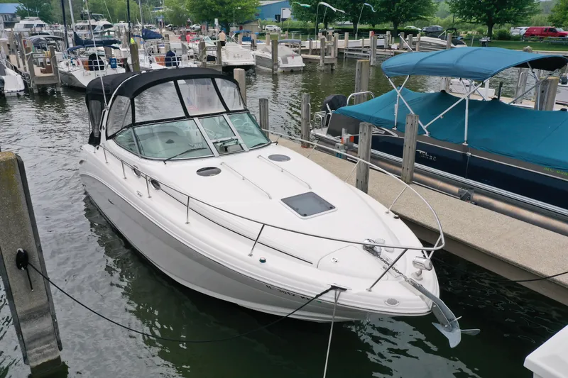 Slide: The Image of 2006 Sea Ray 300 Sundancer docked at marina, featuring sleek white design and black canopy. - 6