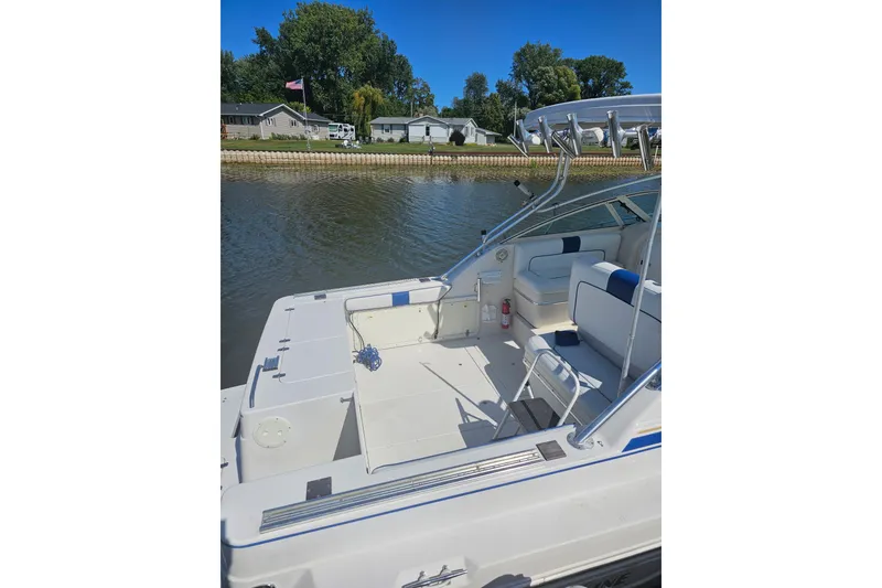 Slide: The Image of 1998 Pro-Line 3250 Express boat with spacious deck, docked by a waterfront home. - 2