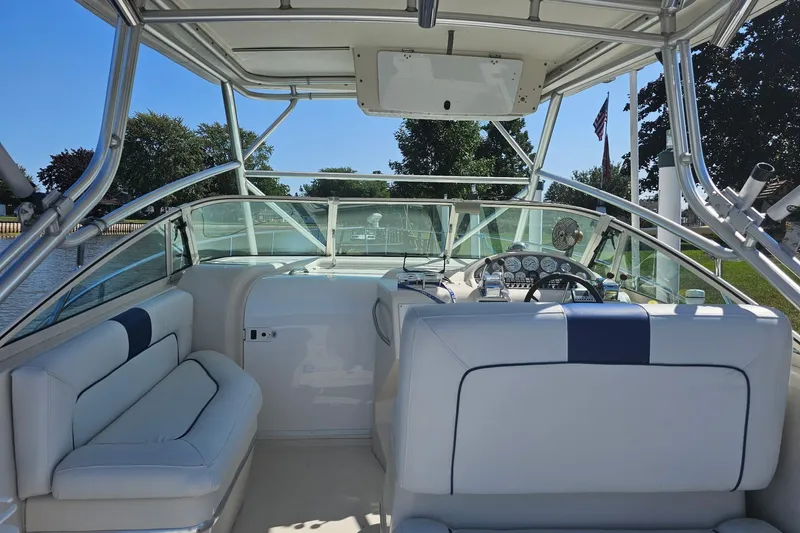 Slide: The Image of 1998 Pro-Line 3250 Express boat interior with seating and control panel, docked by a scenic waterfront. - 4
