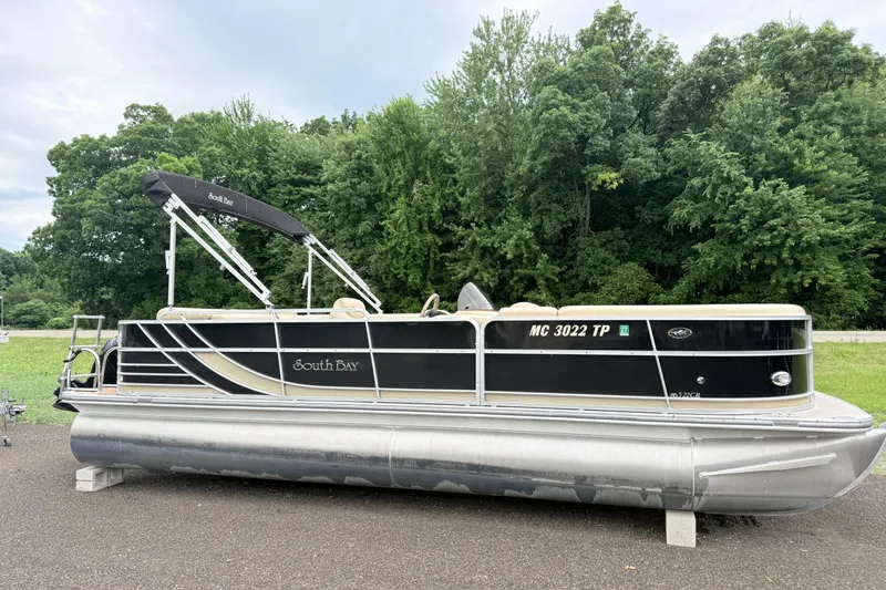 The Image of 2013 South Bay 522CR pontoon boat parked on asphalt with lush green trees in the background. - 0