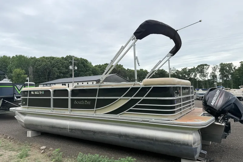 Slide: The Image of 2013 South Bay 522CR pontoon boat with Mercury outboard motor, parked outdoors. - 2