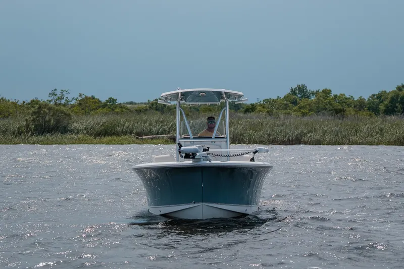 Slide: The Image of 2022 Sea Hunt Ultra 229 boat cruising on a calm lake with lush greenery. - 1