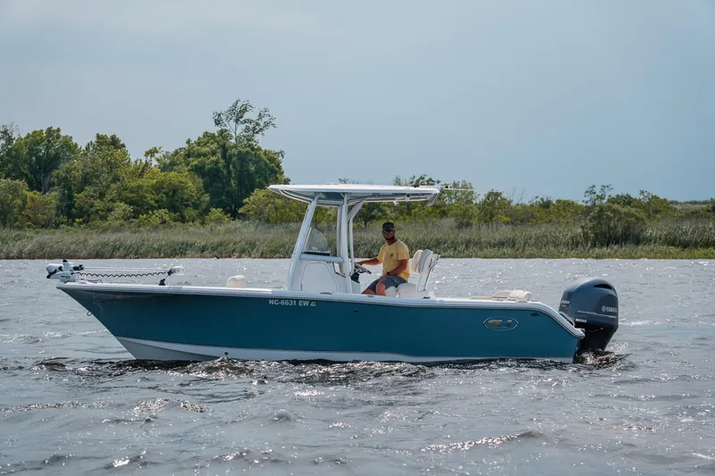 Slide: The Image of 2022 Sea Hunt Ultra 229 boat cruising on a lake with lush greenery in the background. - 3
