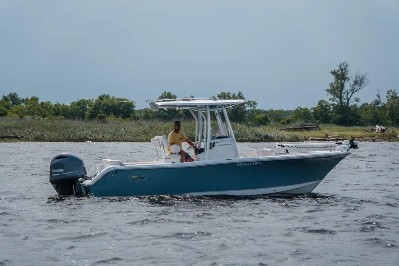 Slide: The Image of 2022 Sea Hunt Ultra 229 boat cruising on a lake with lush greenery in the background. - 5