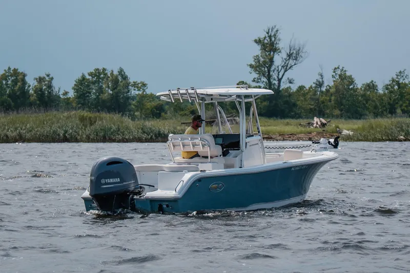 Slide: The Image of 2022 Sea Hunt Ultra 229 boat on water with Yamaha engine, near lush shoreline. - 7