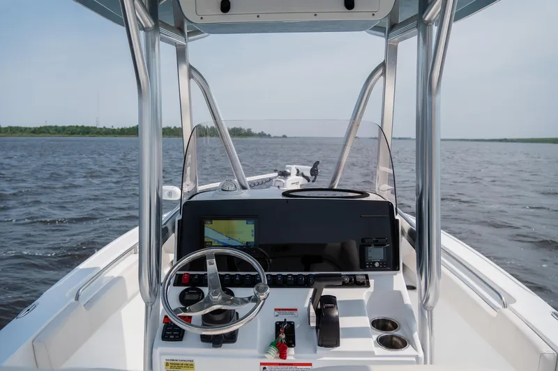 Slide: The Image of 2022 Sea Hunt Ultra 229 boat dashboard with steering wheel and navigation system on open water. - 9