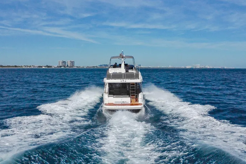Slide: The Image of 2025 Beneteau Swift Trawler 41 Fly cruising on open sea, city skyline in background. - 4