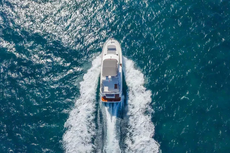 Slide: The Image of 2025 Beneteau Swift Trawler 41 Fly cruising on open blue sea, aerial view. - 6