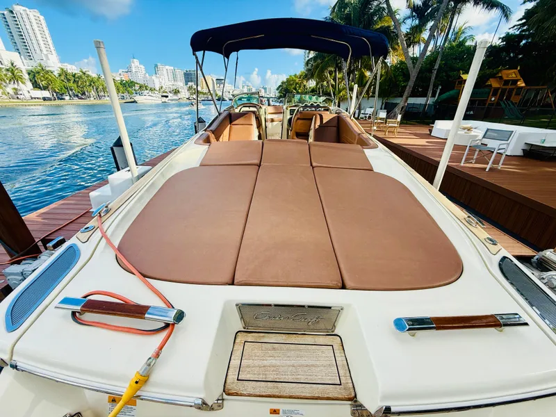 Slide: The Image of 2015 Chris-Craft Launch 32 boat docked by a scenic waterfront with palm trees. - 14