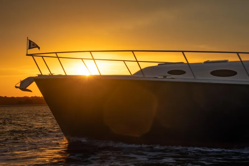 Slide: The Image of 2018 Palm Beach Motor Yachts 55 silhouetted against a vibrant sunset on the water. - 11