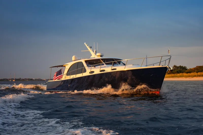 Slide: The Image of 2018 Palm Beach Motor Yachts 55 cruising on open water at sunset. - 2