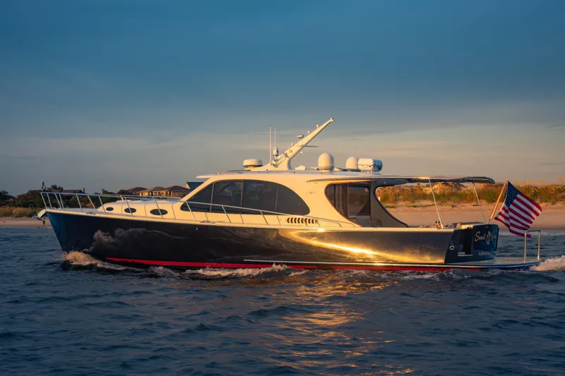 Slide: The Image of 2018 Palm Beach Motor Yachts 55 cruising near the shore at sunset. - 6