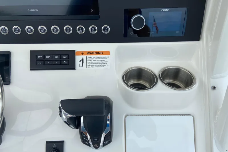 Slide: The Image of 2027 Regulator 26XO boat dashboard with controls, warning label, and cup holders. - 27
