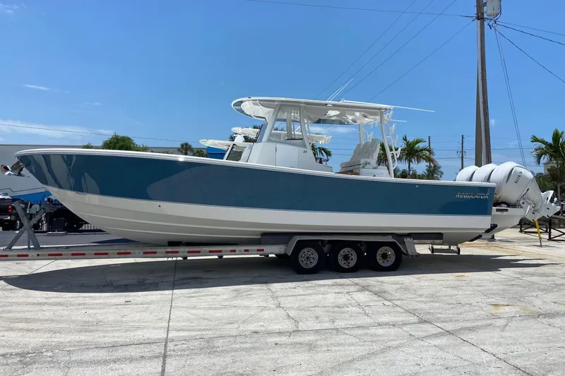 Slide: The Image of 2027 Regulator 35 boat on trailer, blue and white design, parked outdoors. - 1